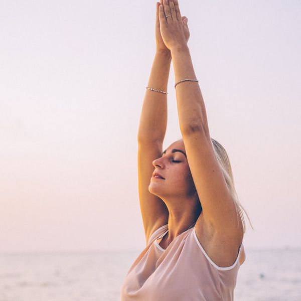 Person stretching peacefully outdoors at sunrise.